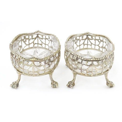 586 - A pair of Geo III silver salts with openwork decoration and raised on ball and claw feet, with clear... 