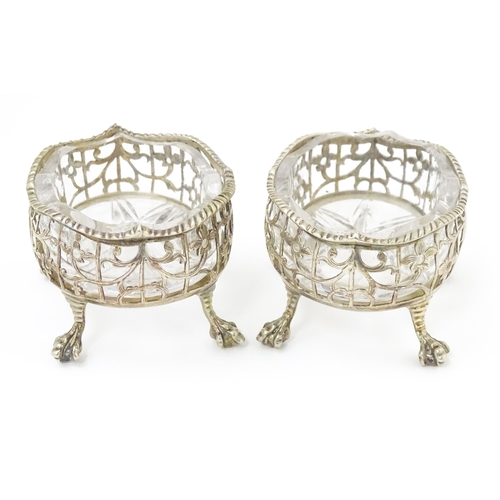 586 - A pair of Geo III silver salts with openwork decoration and raised on ball and claw feet, with clear... 