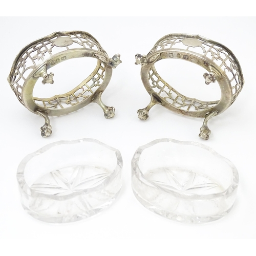 586 - A pair of Geo III silver salts with openwork decoration and raised on ball and claw feet, with clear... 