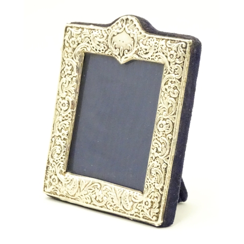 607 - An easel back photograph frame with embossed silver surround hallmarked London 1997, maker Kitney & ... 