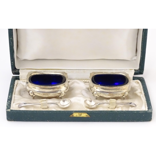 674 - A cased pair of silver salts with blue glass liners, hallmarked London 1910, maker Reid & Sons. With... 