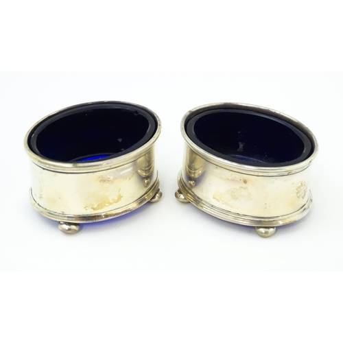 678 - A pair of silver salts of oval form with blue glass liner, hallmarked Birmingham 1921, maker H. J. C... 