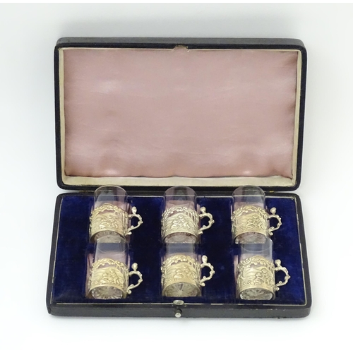 680 - A cased set of six tot glasses with silver holders hallmarked Birmingham 1911, maker William Comyns ... 