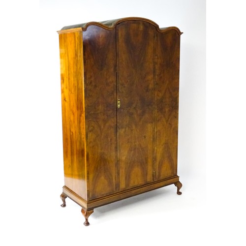 1830 - An Art Deco style walnut wardrobe with a shaped cornice above a single panelled door raised on a det... 