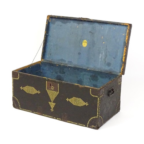 1865 - A 19thC trunk with a leather exterior and brass stud detailing, the chest flanked by wrought iron ca... 