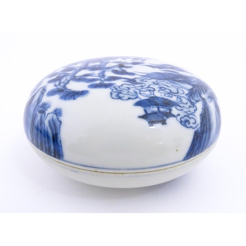 24 - A Chinese blue and white ink box of circular form decorated with figures in a landscape scene with a... 