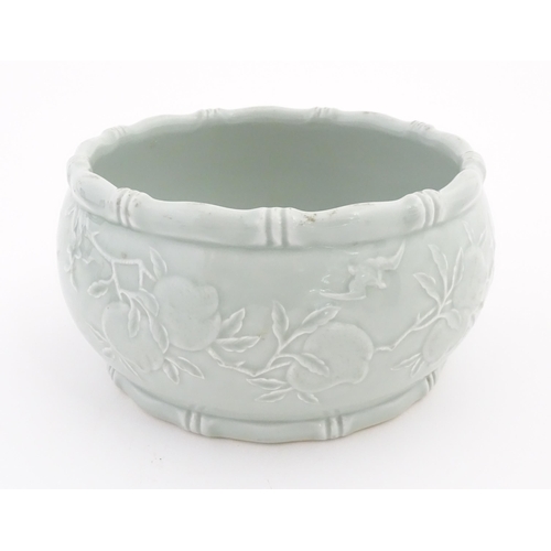 46 - A Chinese celadon planter decorated in relief with peaches and bat detail, and stylised bamboo rims.... 
