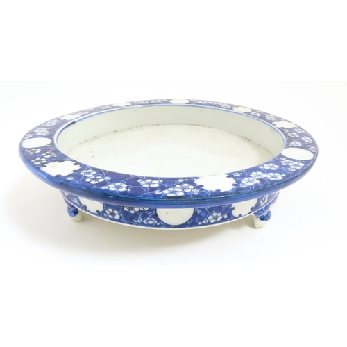 53 - A Chinese blue and white stand of circular form raised on three feet decorated with prunus flowers. ... 