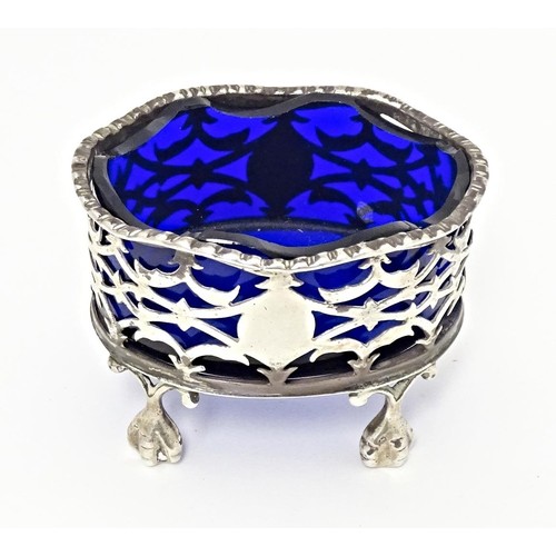 384 - A Victorian silver salt with pierced decoration and blue glass liner, standing on four ball and claw... 