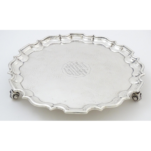 451 - A silver salver with hammered decoration and raised on three feet, hallmarked London 1903, maker Tho... 