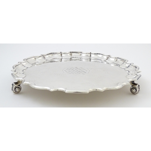 451 - A silver salver with hammered decoration and raised on three feet, hallmarked London 1903, maker Tho... 