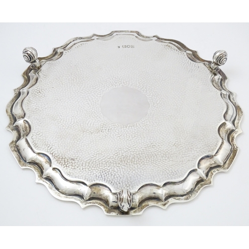 451 - A silver salver with hammered decoration and raised on three feet, hallmarked London 1903, maker Tho... 