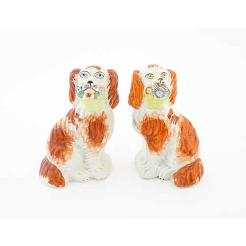 57 - A pair of Victorian Staffordshire pottery dogs, each holding a basket of flowers. Approx. 8