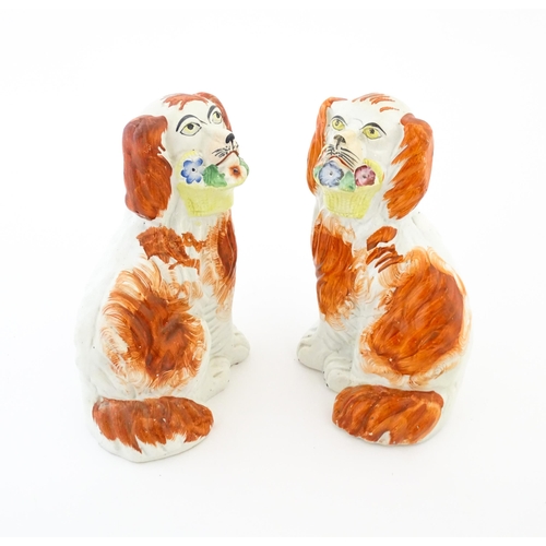 57 - A pair of Victorian Staffordshire pottery dogs, each holding a basket of flowers. Approx. 8