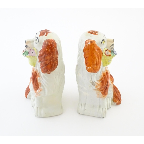 57 - A pair of Victorian Staffordshire pottery dogs, each holding a basket of flowers. Approx. 8