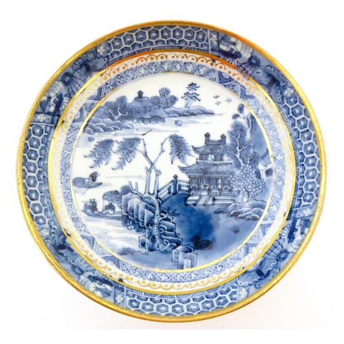 65 - A blue and white dish with hand painted chinoiserie river scene with figures in boats by a pagoda st... 