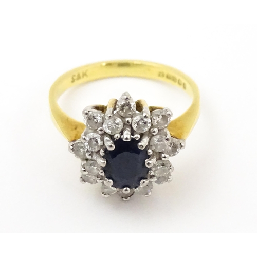 827 - An 18ct gold ring set with a central sapphire bordered by diamonds. Ring size approx. J 1/2