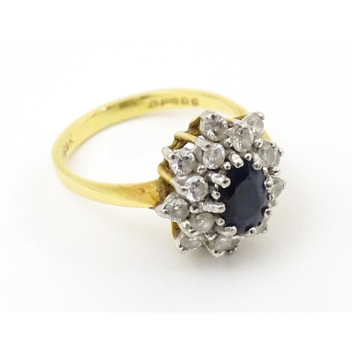 827 - An 18ct gold ring set with a central sapphire bordered by diamonds. Ring size approx. J 1/2