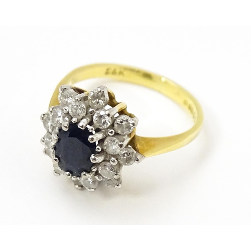 827 - An 18ct gold ring set with a central sapphire bordered by diamonds. Ring size approx. J 1/2