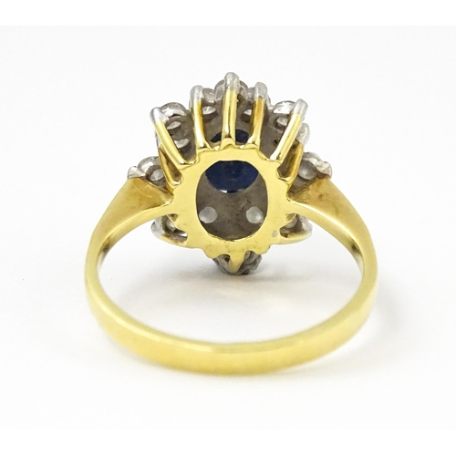 827 - An 18ct gold ring set with a central sapphire bordered by diamonds. Ring size approx. J 1/2