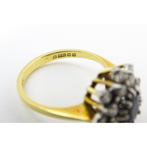 827 - An 18ct gold ring set with a central sapphire bordered by diamonds. Ring size approx. J 1/2