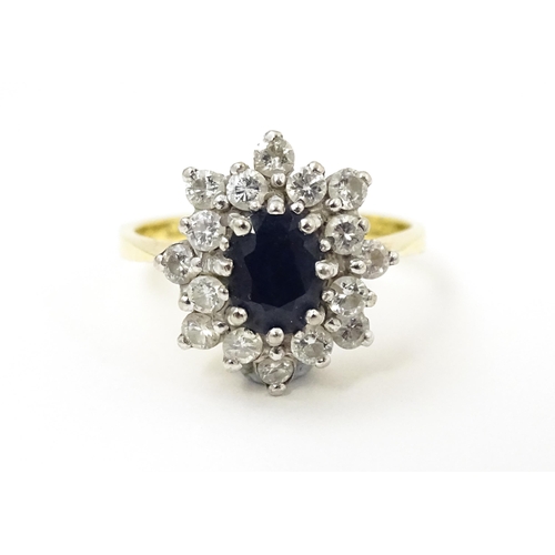 827 - An 18ct gold ring set with a central sapphire bordered by diamonds. Ring size approx. J 1/2