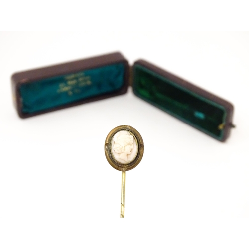 834 - A late 19thC / early 20thC gilt metal stick pin surmounted by a cameo. Approx 3