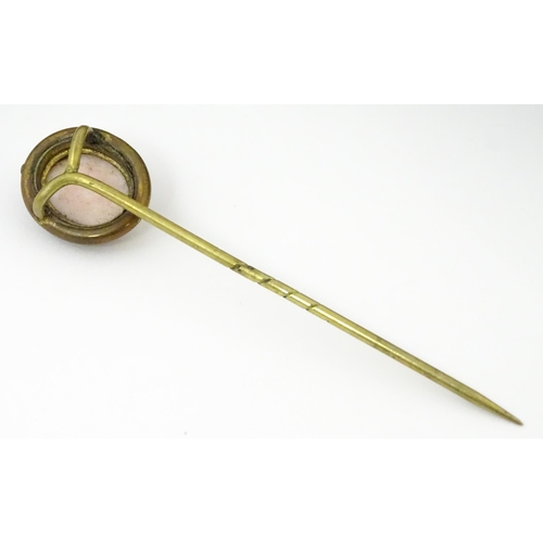 834 - A late 19thC / early 20thC gilt metal stick pin surmounted by a cameo. Approx 3