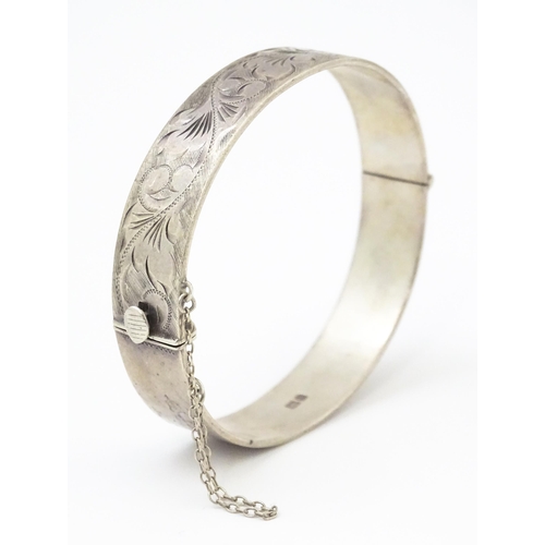 866 - A silver bracelet of bangle form with engraved acanthus scroll decoration hallmarked Birmingham 1976... 