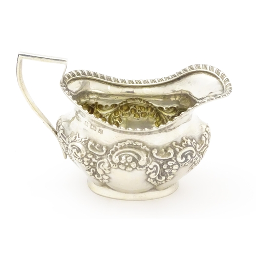 286 - A silver cream jug with embossed floral and foliate decoration hallmarked Birmingham 1903, maker W. ... 