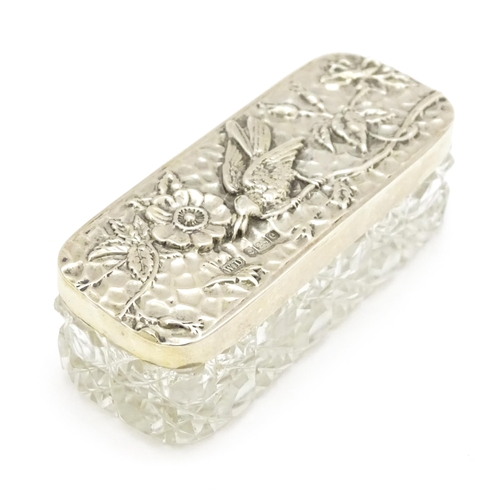 292 - A cut glass dressing table box the silver lid with embossed flower and bird detail, hallmarked Birmi... 