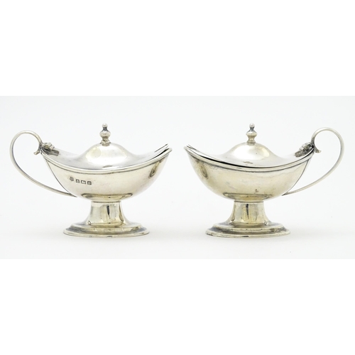 298 - A pair of silver mustard pots with blue glass liners hallmarked Birmingham 1918, maker J. Sherwood &... 