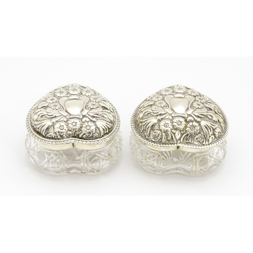 372 - A matched pair of cut glass dressing table pots of heart form with embossed silver lids, hallmarked ... 