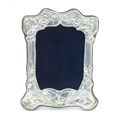 452 - An easel back photograph frame with silver surround with embossed Art Nouveau style decoration, hall... 