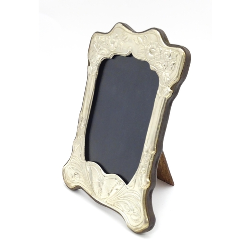 452 - An easel back photograph frame with silver surround with embossed Art Nouveau style decoration, hall... 