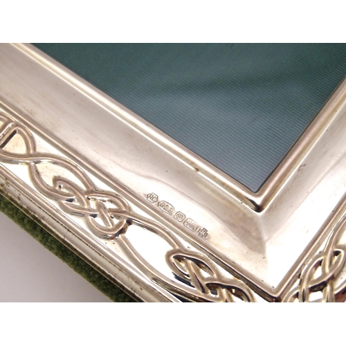 453 - An easel back photograph frame with silver surround decorated with banded Celtic knot detail, hallma... 