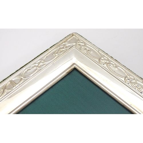 453 - An easel back photograph frame with silver surround decorated with banded Celtic knot detail, hallma... 