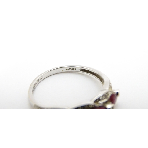 697A - A 9ct white gold ring set with rubies and diamond.  Ring size approx. M 1/2