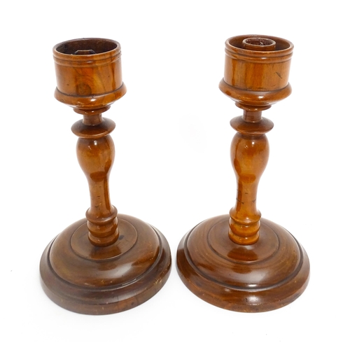 1100 - A pair of treen turned wooden candlesticks. Approx. 9 1/4