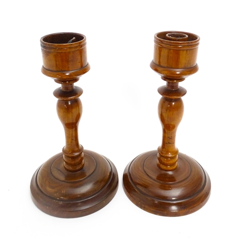 1100 - A pair of treen turned wooden candlesticks. Approx. 9 1/4