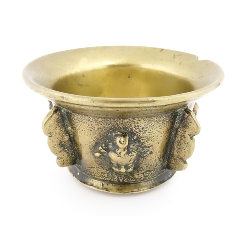 1115 - A small late 17th / early 18thC bronze mortar with mask / cherub head detail. Approx. 2 3/4