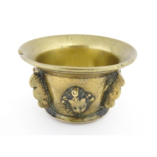 1115 - A small late 17th / early 18thC bronze mortar with mask / cherub head detail. Approx. 2 3/4