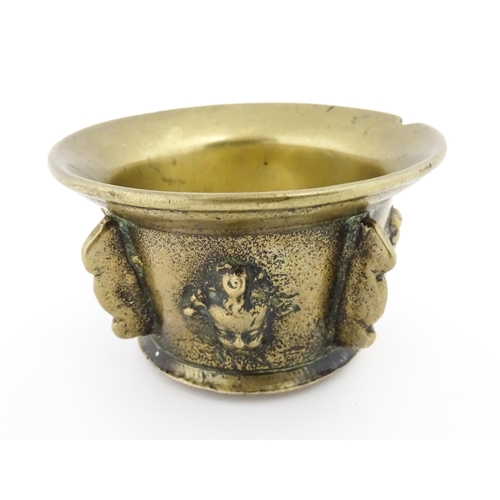 1115 - A small late 17th / early 18thC bronze mortar with mask / cherub head detail. Approx. 2 3/4