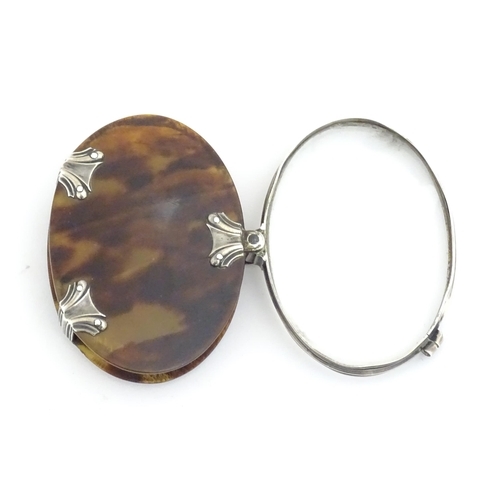 1202 - A Victorian folding magnifying glass of oval form, the tortoiseshell cover with white metal mounts. ... 