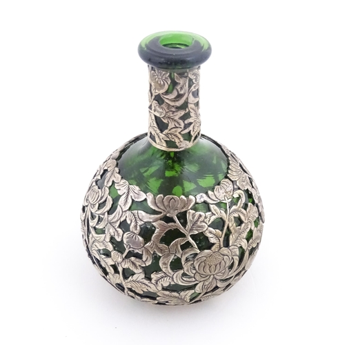 215 - A green glass perfume / scent bottle with white metal floral and foliate overlay in the Oriental sty... 