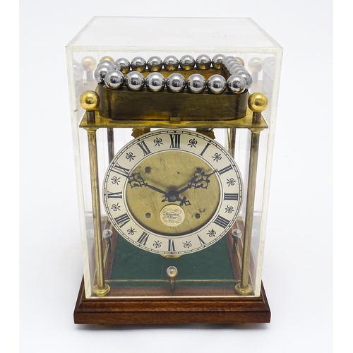1434 - A Thwaites & Reed rolling ball clock, the open movement with silvered dial with Roman numerals and n... 