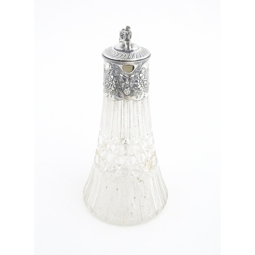 250 - A late 19th / early 20thC cut glass claret jug with silver plate mounts, the lid surmounted by a sty... 