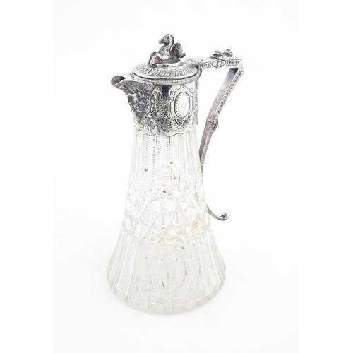 250 - A late 19th / early 20thC cut glass claret jug with silver plate mounts, the lid surmounted by a sty... 