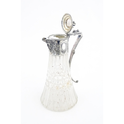 250 - A late 19th / early 20thC cut glass claret jug with silver plate mounts, the lid surmounted by a sty... 