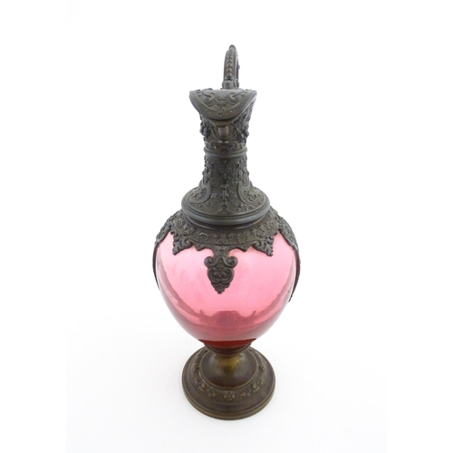 251 - A Victorian cranberry glass claret jug with decorative metal mounts and handle. Approx. 13